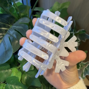 Detail of a pearl white snowflake hair claw clip with glossy finish and sturdy teeth