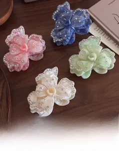 Detailed close-up of acetate floral hair claws with rhinestones in four soft colors