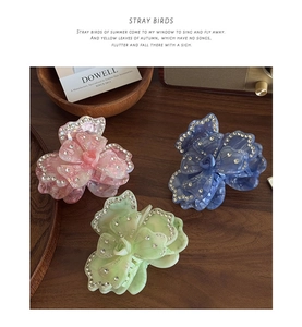Detail of multi-color acetate flower hair claws with rhinestones on a wooden surface