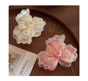 Detailed close-up of acetate flower hair claws with sparkling rhinestones on wood
