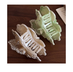 Detailed macro of marble texture butterfly hair claws with rhinestones in green and beige