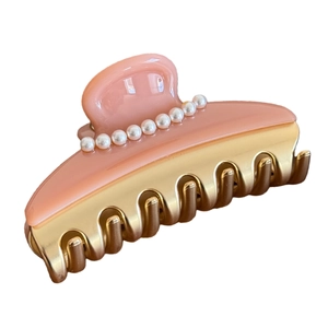 Elegant pink acetate hair claw clip with white pearls and gold metal base in a studio shot