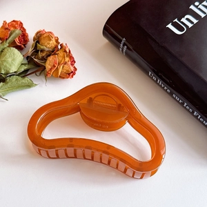 Nahaufnahme der eleganten 11cm Haarklammer aus Bernstein-Harz mit Wellendesign auf Buch