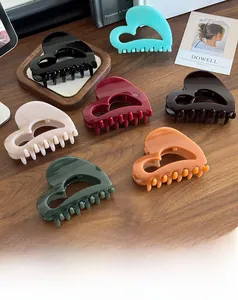 Detail showing various colors of heart-shaped hollow hair claws on a wooden surface