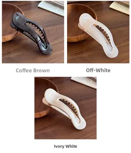 Vue détaillée de grandes pinces à cheveux en café, blanc crème et ivoire sur bois