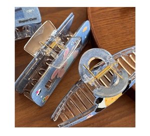 Detail of blue denim pattern hair claw clips with cartoon icons and metal spring