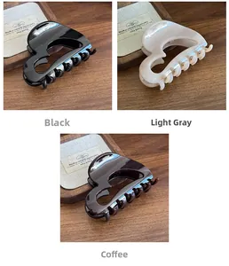 Detailed view of large heart-shaped hair claws in black, beige, and coffee brown acrylic
