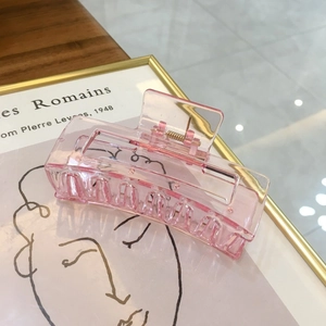 Detailansicht einer großen rosa Haarspange mit goldener Feder und hohlem Design-Element