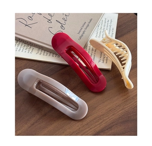 Détail de barrettes rouges et beiges avec une pince à cheveux crème sur bois sombre