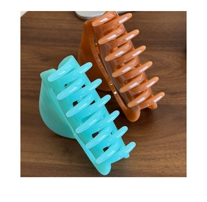 Detail of mint green and amber orange large hair claws on a dark wood background