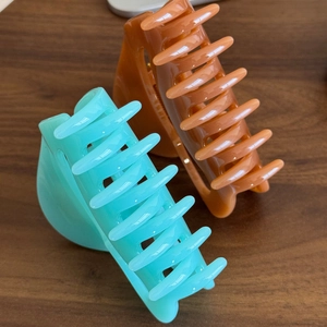 Large pumpkin hair claw clips in mint green and amber brown on wood background