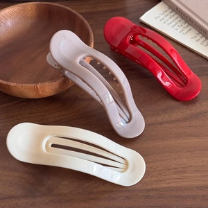 Trois pinces à cheveux minimalistes en résine PC en blanc crème, rose et rouge sur bois