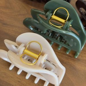 Vintage large pumpkin claw clips in beige and dark green on warm wood surface