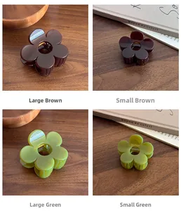 Close-up of flower-shaped hair claws in green and brown on a wooden surface