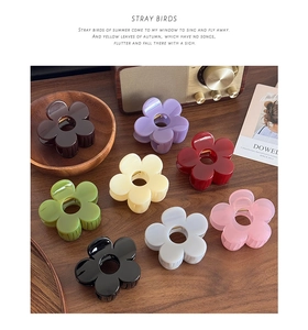 Set of eight floral hair claws in assorted colors displayed on a vintage wooden table