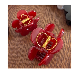 Detail shot of the glossy red flower hair claw with a high-quality metal spring mechanism