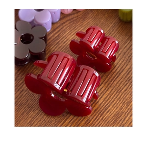 Detailed view of the wine red flower hair claw clip on a textured wooden background