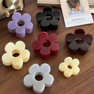 Elegant floral hair claws set in various colors on a vintage walnut wood background