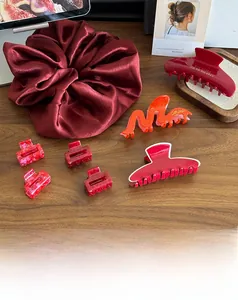 Gros plan d'accessoires rouges avec chouchou en satin et pinces à cheveux marbrées