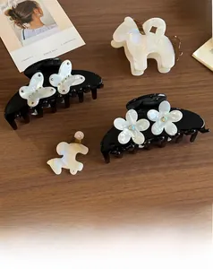 Dettaglio di fermagli per capelli in acetato a forma di cavallo, colori nero e crema