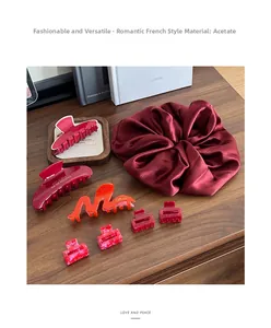 Gros plan de pinces à cheveux en acétate rouge et chouchou assorti sur un bureau en bois