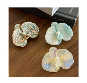 Dettaglio di fermagli per capelli a orchidea con perle su fondo in legno vintage