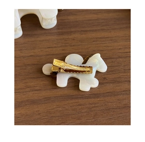 Dettaglio della clip in metallo dorato e fermaglio per capelli pony perlato su legno