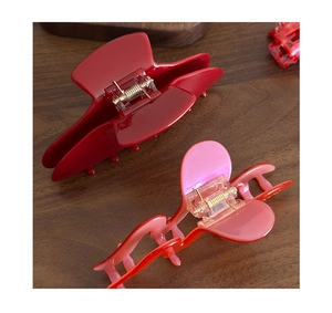 Détail d'une pince à cheveux rouge foncé et d'un accessoire rose pailleté en résine de qualité