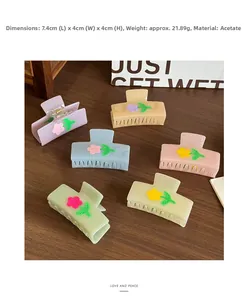 Detail view of acetate flower hair claws in multiple pastel colors on wood surface