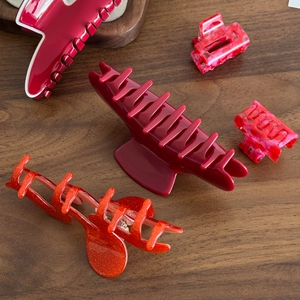Assortiment de pinces à cheveux rouges et roses de tailles variées sur bois sombre