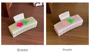 Detail of square hair claws with 3D flower designs in pearlescent green and purple finishes