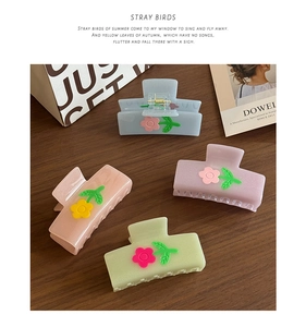 Detailed view of four colorful acetate flower hair claws on a rustic wooden table background