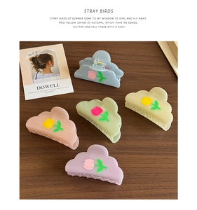 Detail view of 5-piece acetate tulip hair claw clips in macaron colors on wood surface
