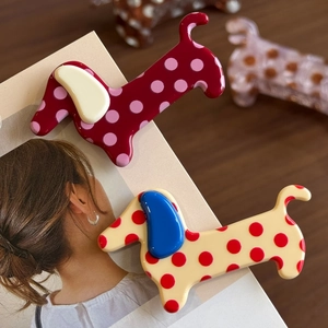 Cute dachshund puppy hair claws with polka dot patterns on a brown wooden background
