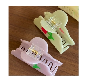 Detail of macaron tulip hair claws showing pearlescent acetate finish and gold spring
