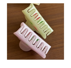 Detail of yellow and pink acetate hair claws with subtle glitter on a wood surface