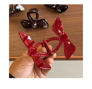 Detail of red butterfly hair claw clip showing internal metal spring and resin teeth