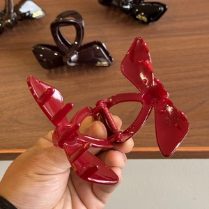 Elegant bow-shaped hair claw clip in glossy burgundy finish for high ponytail styling