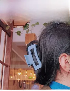 Détail d'une pince à cheveux rectangulaire bleu mat portée par un mannequin en studio