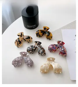 Vue à plat de pinces à cheveux en acétate aux motifs écaille et marbre sur fond blanc