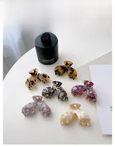Vue à plat de six pinces à cheveux en acétate aux motifs écaille de tortue et marbre sur table