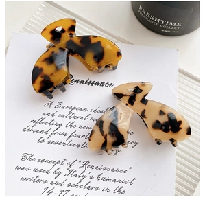 Détail de pinces à cheveux en acétate motif écaille de tortue ambre foncé et beige clair