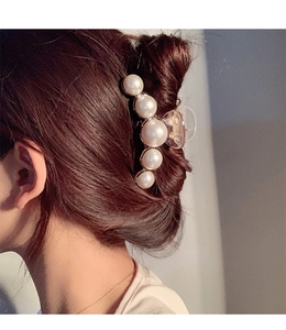 Pince à cheveux élégante avec perles dégradées portée sur un chignon, style raffiné
