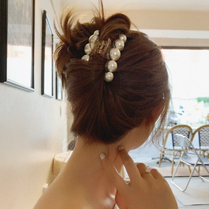 Pince à cheveux transparente avec perles élégantes portée sur cheveux bruns