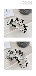 Dettaglio di mollette per capelli con motivo mucca bianco e nero in design geometrico e a fiocco