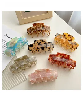 Detailed view of large acrylic hair claws in assorted patterns on a white surface