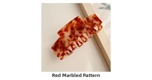 Detail of large marble-patterned hair claw clip in red and brown tortoiseshell finish