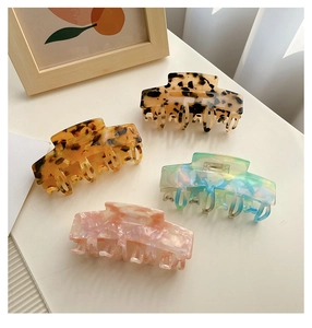 Flat lay of four large acetate hair claws in tortoise shell and floral patterns