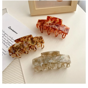 Three large tortoiseshell hair claws in brown, beige, and cream colors on a white background