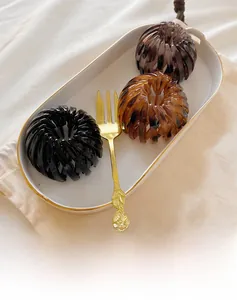 Three bird nest hair clips in black, tortoiseshell, and brown on a white plate